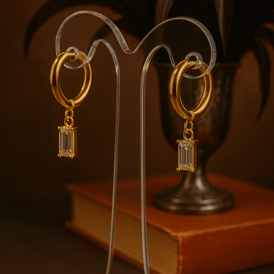 A gold-plated huggie hoop earring featuring an emerald-cut clear cubic zirconia drop