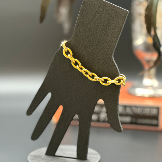 18K gold plated mariner link bracelet on a woman's wrist with dark textured background