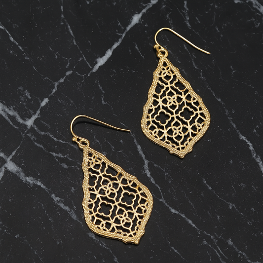 morrocan style gold earrings laying on a piece of black granite with white veins