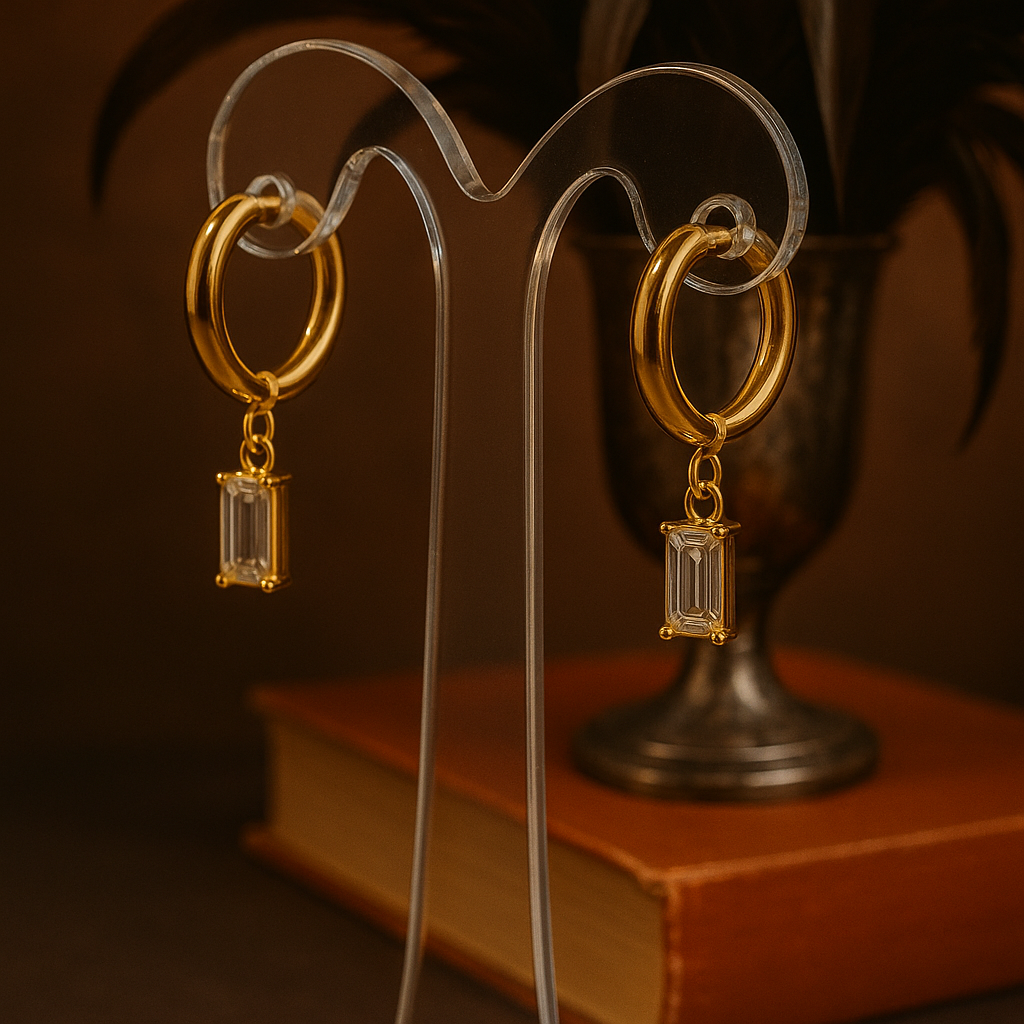 A gold-plated huggie hoop earring featuring an emerald-cut clear cubic zirconia drop