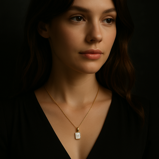 Woman wearing a gold necklace with a square pendant against a dark background