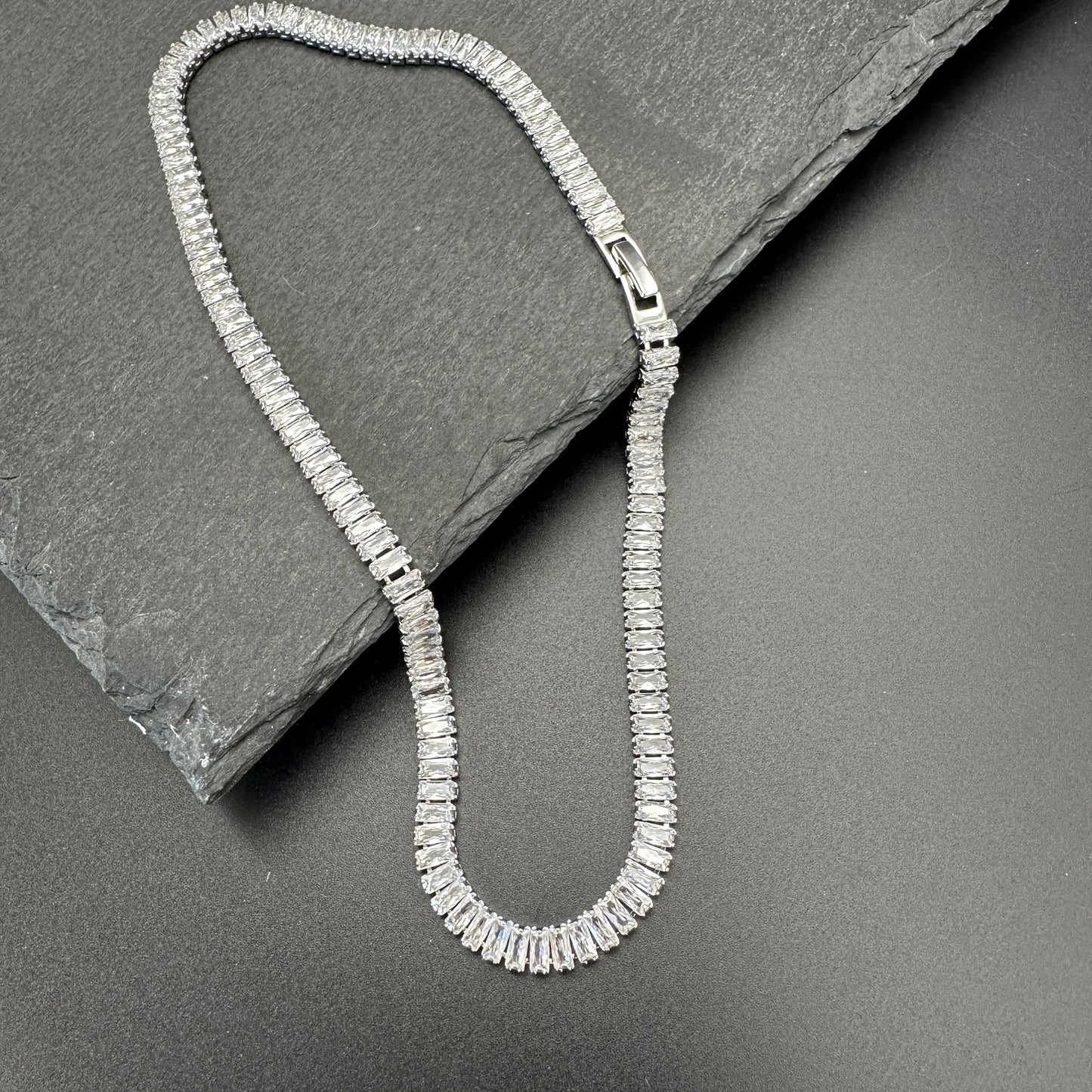 Silver necklace on a dark stone surface