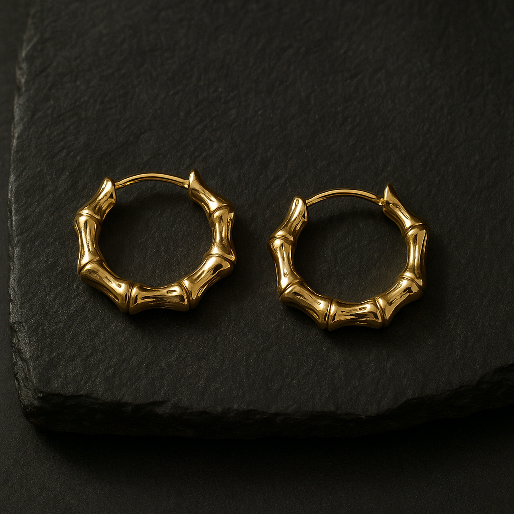 Pair of 18 K gold-plated bamboo-style mini hoop earrings on dark granite with top-right lighting