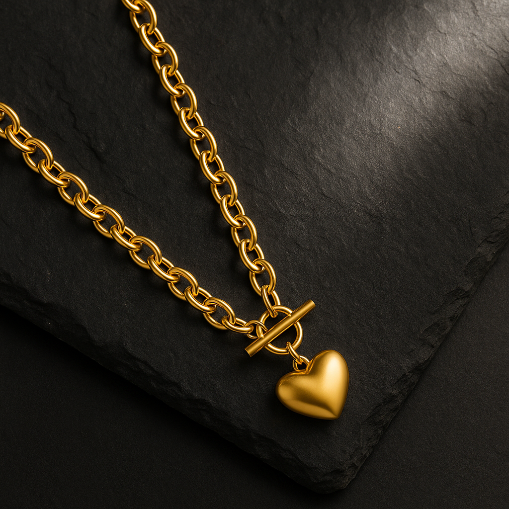 Flat lay of the gold heart toggle necklace on dark granite with directional lighting from upper right.