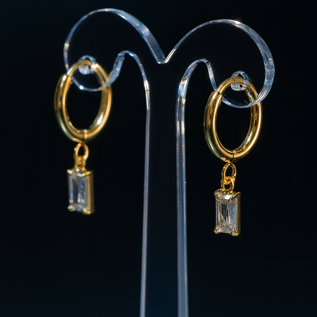 A gold-plated huggie hoop earring featuring an emerald-cut clear cubic zirconia drop