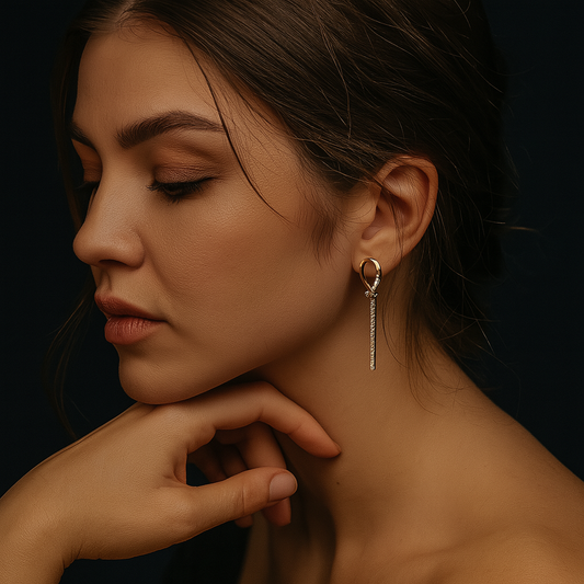 Woman with warm olive skin wearing a gold pavé teardrop-bar drop earring in a moody portrait